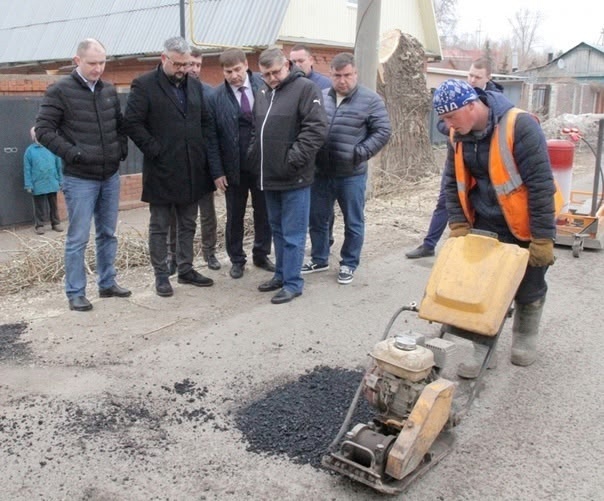 Трое рабочих в потрёпанных жилетах сосредоточенно утр...